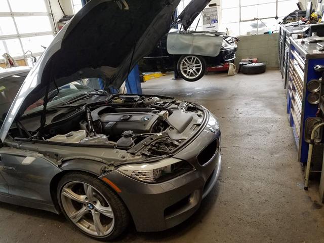 Gray BMW Z4 roadster with the hood open, showing the engine