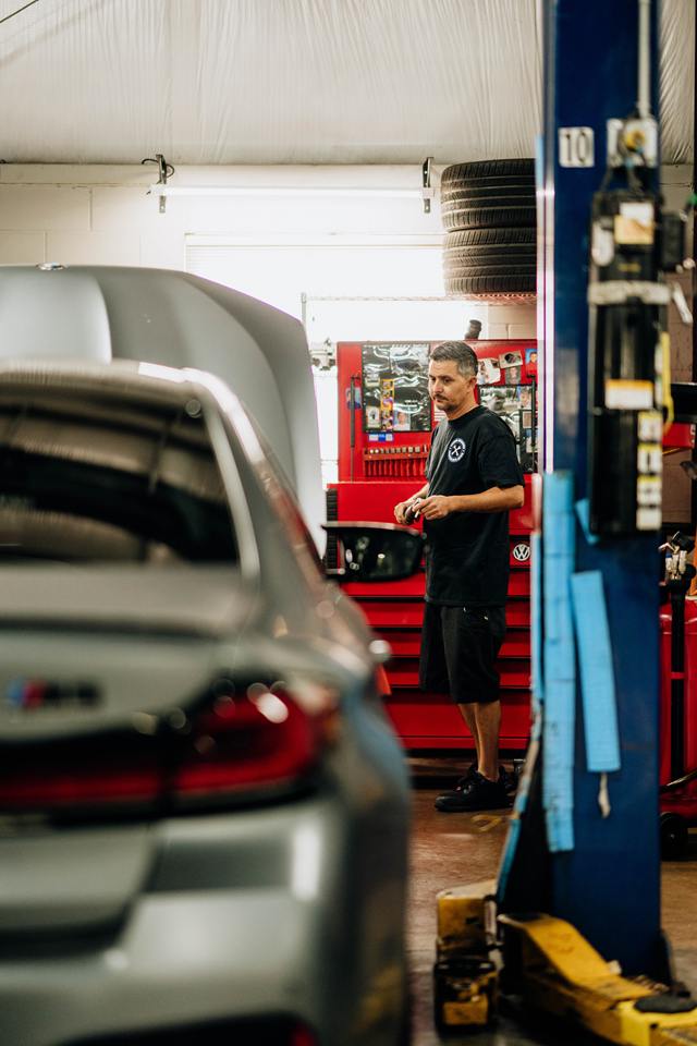 Technician beside a silver BMW M5 in the service bay