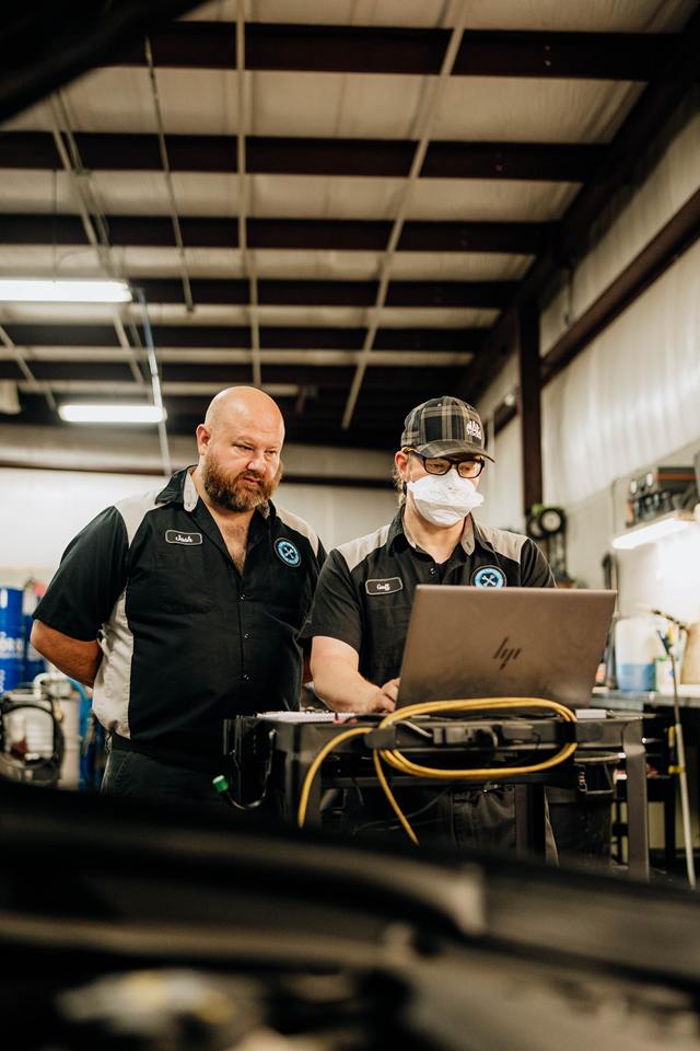 Two technicians reviewing diagnostic data on a laptop