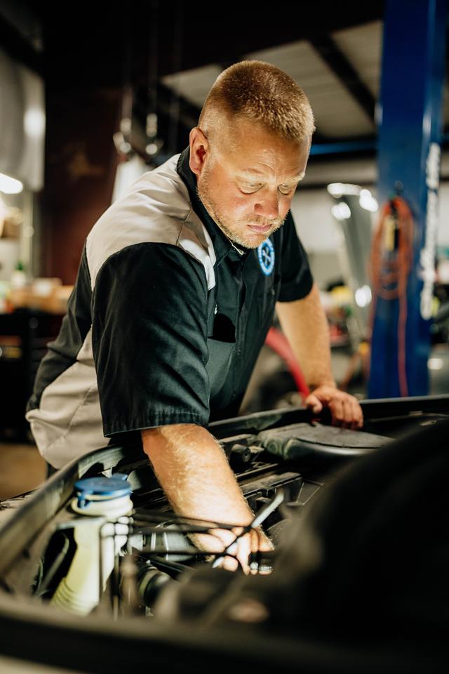 Technician working on an engine with a hand tool