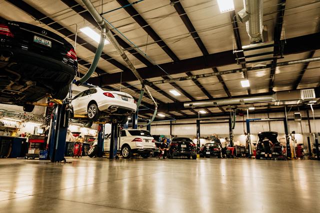 Turning Wrenches service bays with a black Mercedes-Benz sedan and white SUVs raised on lifts