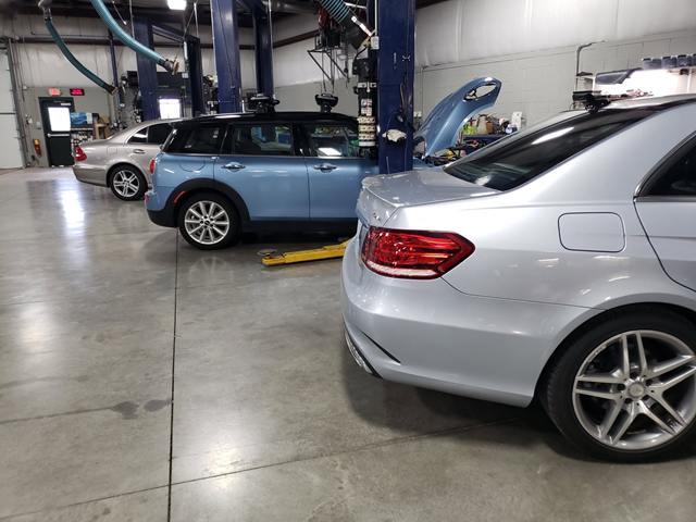 Light blue MINI and a silver Mercedes-Benz sedan in the service bays