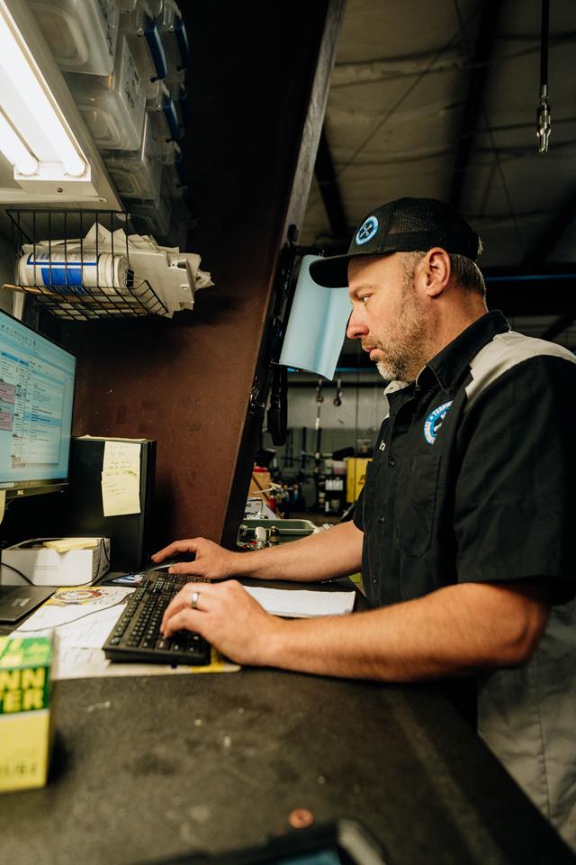 Technician entering repair notes at a shop workstation