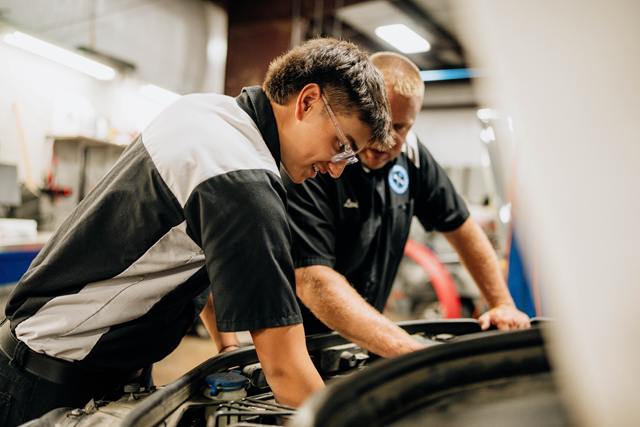Two technicians working in an engine bay