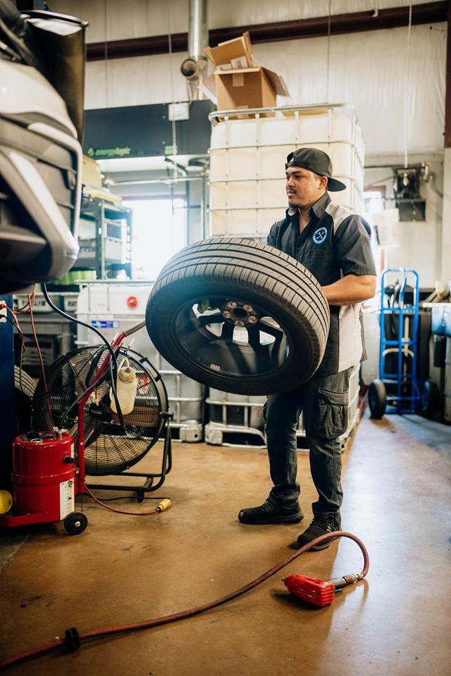 Technician carrying a wheel and tire across the shop