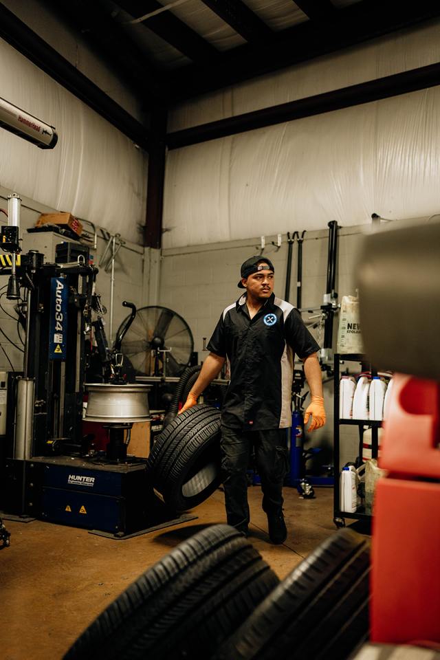 Technician rolling a tire past the Hunter tire changer