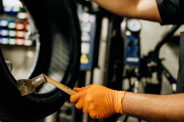 Technician brushing mounting lubricant onto a tire bead