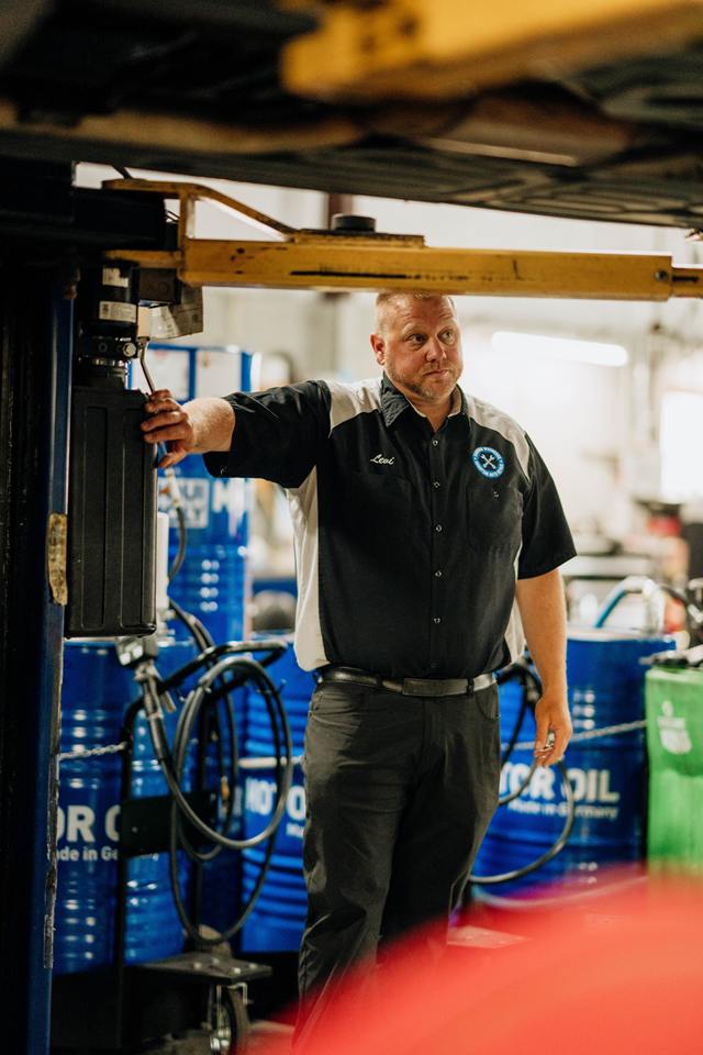 Owner Levi Johnson at the lift controls beside drums of German motor oil
