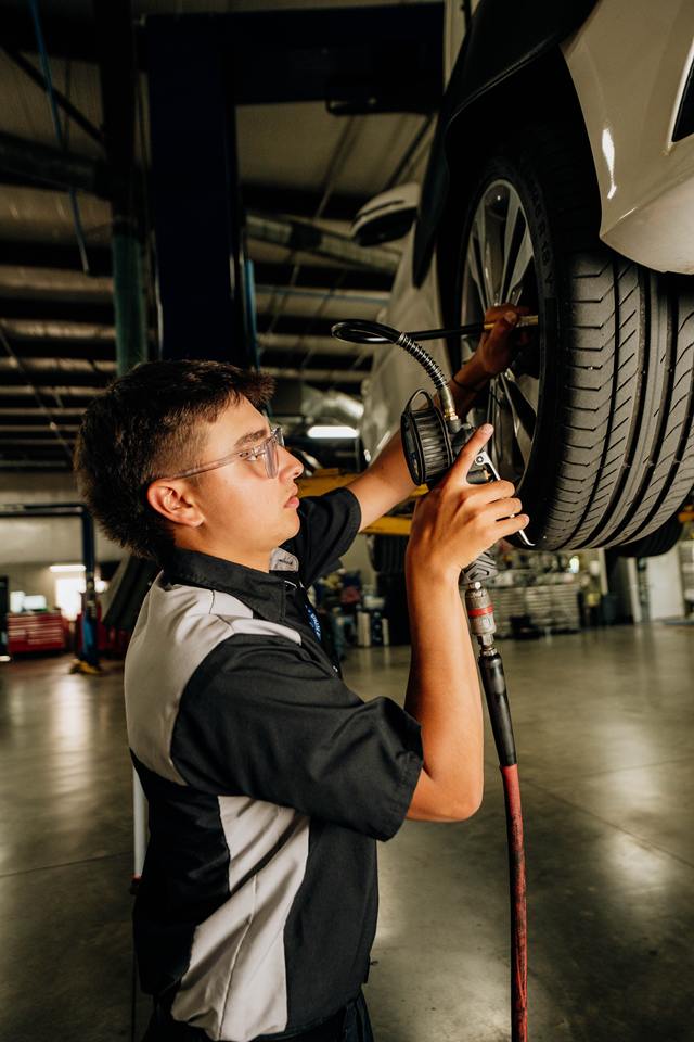 Technician setting tire pressure on a vehicle raised on a lift