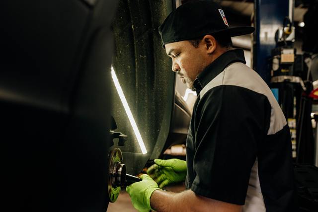 Technician servicing a wheel hub under a work light